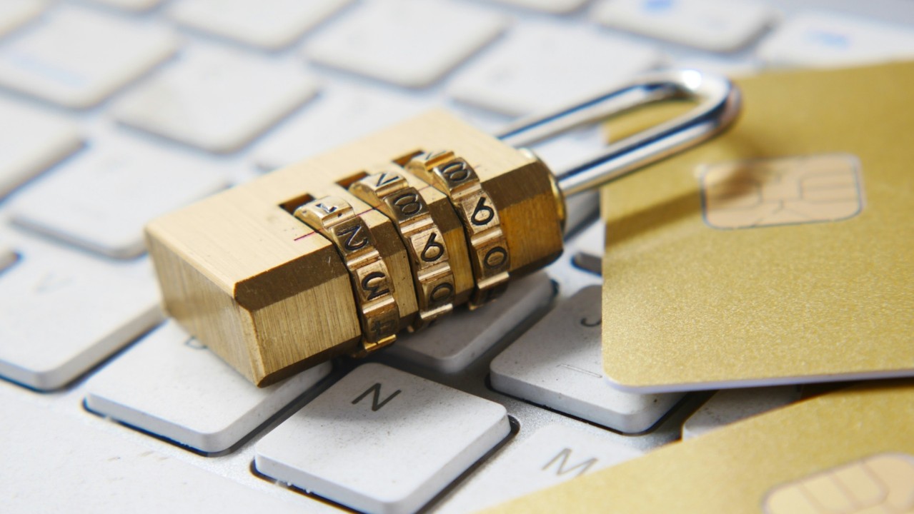 A combination padlock resting on a keyboard with some chip and pin cards